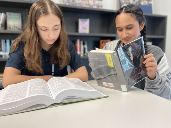 Picture of sophomores  Sara Edelman and Tarini (Rhi) Udipi reading in The Village High School Library.