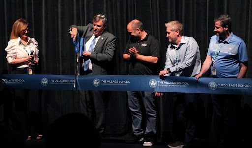 Cut with excitement, Mr. Delbrugge cuts the ribbon to start the performances of the event. Other staff members occupied him at the moment in the auditorium.