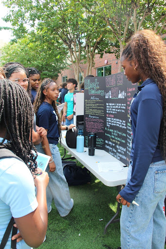 Members of the Black Student Union stand beside their handmade board, while interested students prepare to sign the interest sheet. Left to Right: Members of the Black Student Union Michelle Eronmomhele Uwanguw (10) and Joy Agbasoga (11) stand beside their handmade board showing, while students Nia Washington (10) and Kosi Ezeafulukwe (11) observed the presentation and what it has to offer. (Meyar Elfadul)